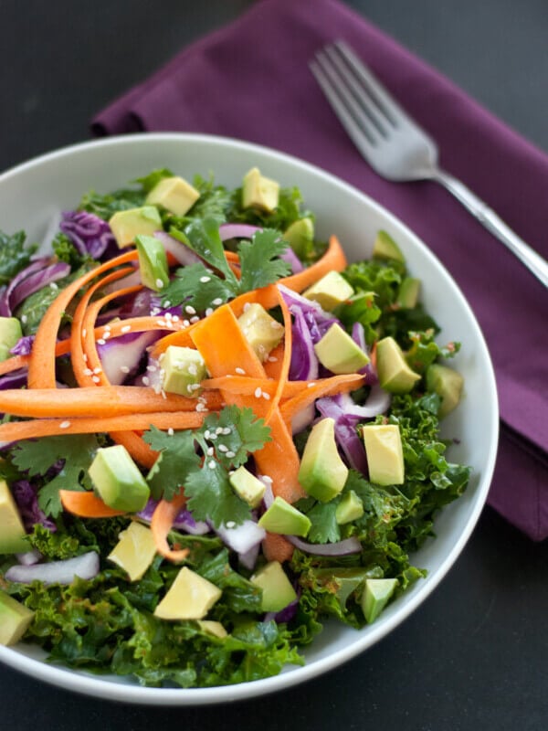 raw salad made with kale, avocado, carrots, and sesame seeds