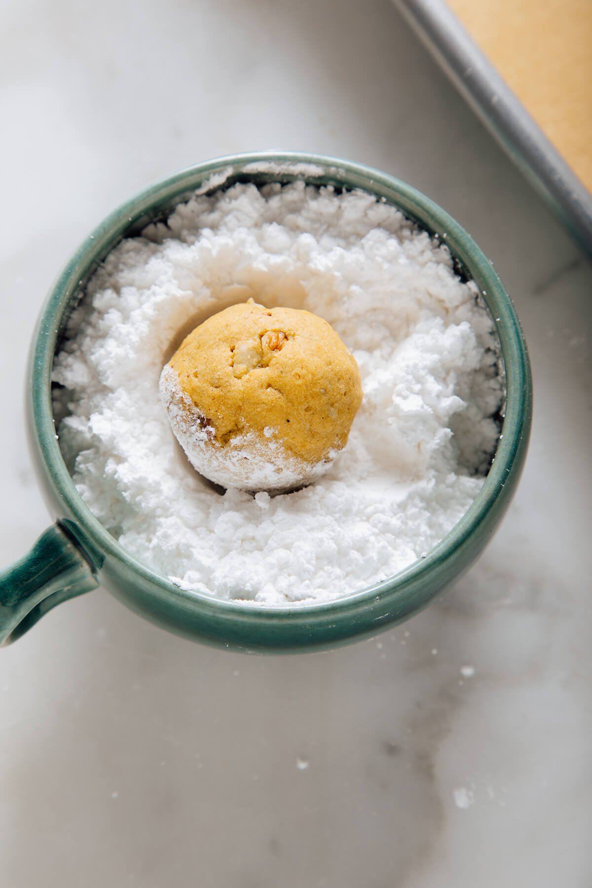 rolling pumpkin polvorones in powdered sugar